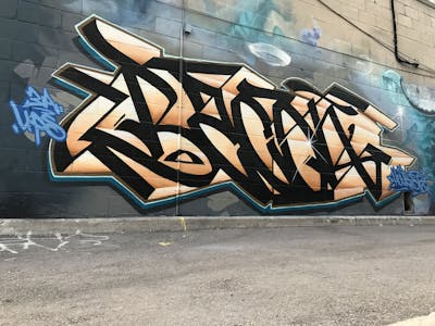 Black and Beige and Cyan Stylewriting by Bacon and exchange with House. This Graffiti is located in Miami, Canada and was created in 2018. This Graffiti can be described as Stylewriting and Wall of Fame.