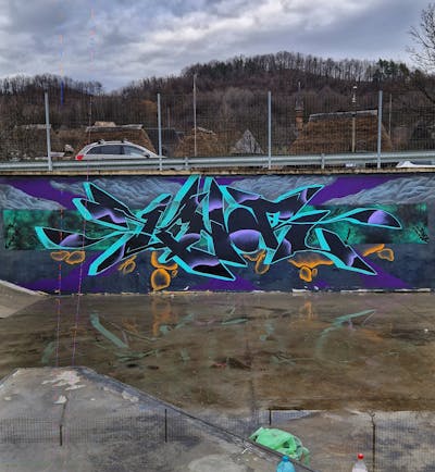 Cyan and Violet Stylewriting by KNOR. This Graffiti is located in Baia Mare, Romania and was created in 2024. This Graffiti can be described as Stylewriting and Wall of Fame.