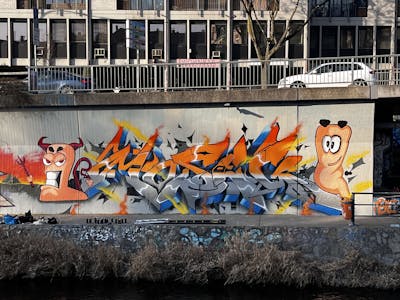 Grey and Orange and Colorful Stylewriting by omseg and Moseg. This Graffiti is located in Freiburg, Germany and was created in 2023. This Graffiti can be described as Stylewriting, Characters and Wall of Fame.