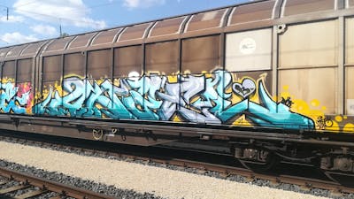 Cyan and Yellow Stylewriting by DCK, ALL CAPS COLLECTIVE and Angel. This Graffiti is located in Hungary and was created in 2021. This Graffiti can be described as Stylewriting, Trains and Freights.