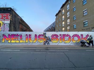 Chrome and Colorful Stylewriting by Nelius, SIDOK and smo__crew. This Graffiti is located in London, United Kingdom and was created in 2023. This Graffiti can be described as Stylewriting, Characters and Wall of Fame.