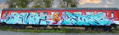 Cyan and Red Stylewriting by azlak and Riots. This Graffiti is located in Jena, Germany and was created in 2022. This Graffiti can be described as Stylewriting, Characters, Trains, Wall of Fame and Freights.