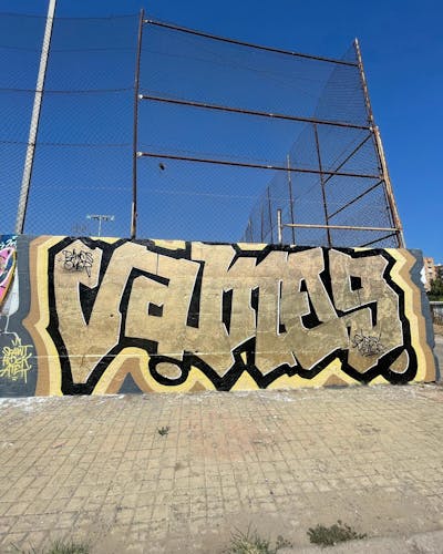 Gold and Black Stylewriting by Vamos. This Graffiti is located in Valencia, Spain and was created in 2022. This Graffiti can be described as Stylewriting and Wall of Fame.